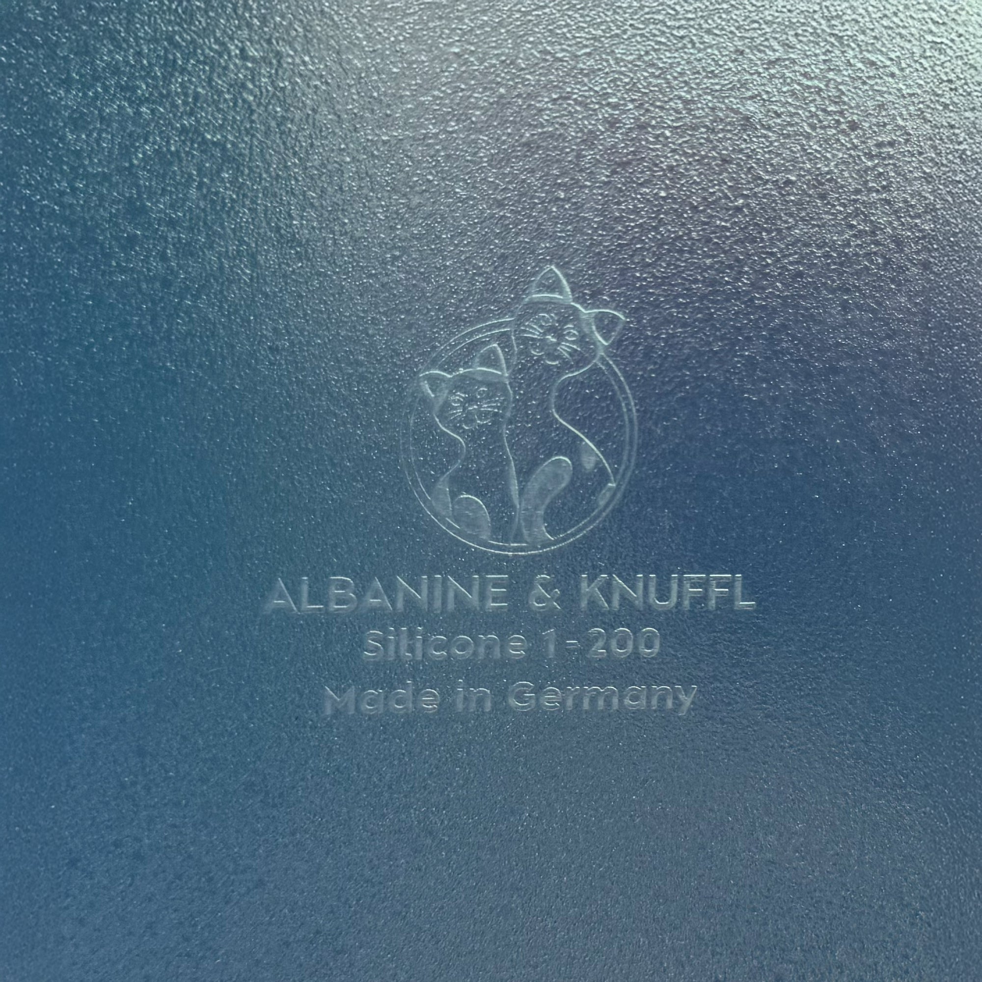 Nahaufnahme Bodenmarke auf Rückseite 8-eckiger farbloser Silikonunterlage für Katzengeschirr, Länge 27,5 cm und Breite 27,5 cm