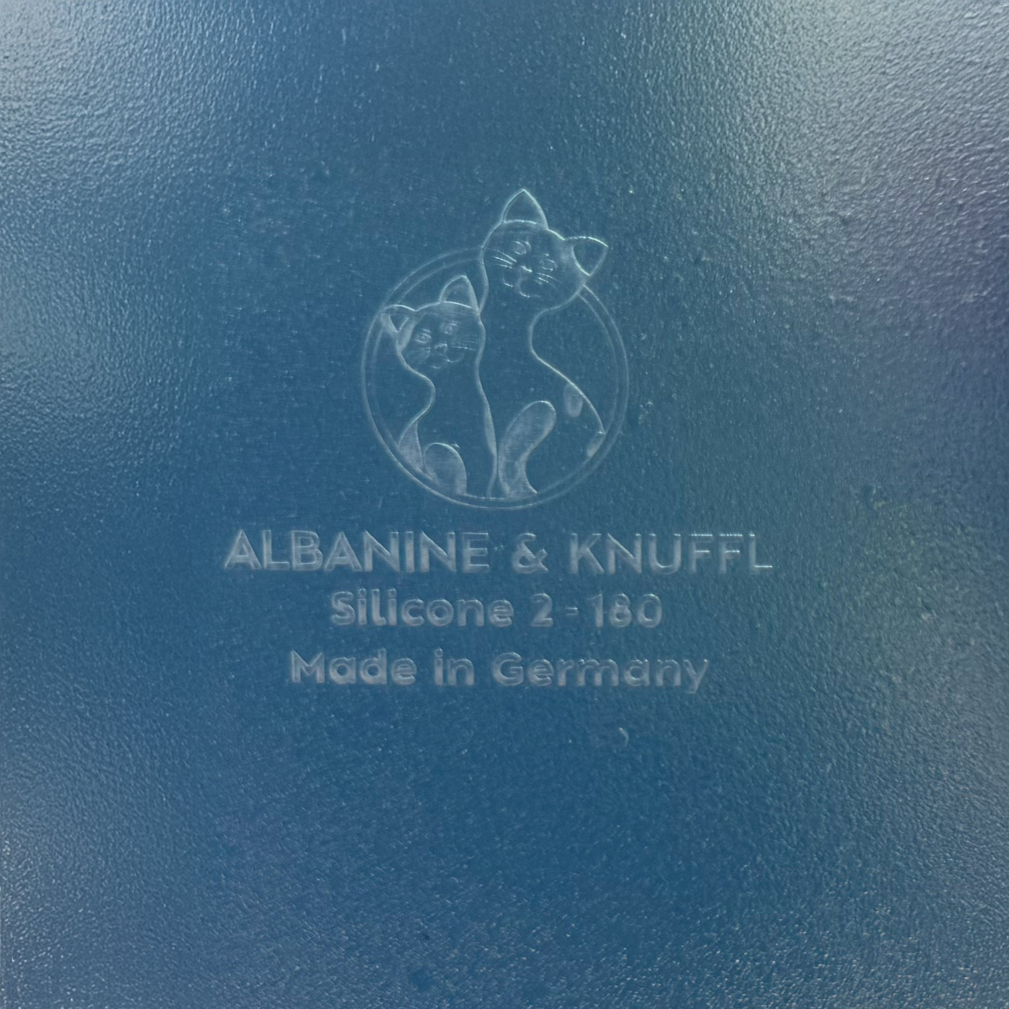 Nahaufnahme Bodenmarke auf Rückseite 8-eckiger farbloser Silikonunterlage für Katzengeschirr, Länge 45 cm und Breite 24,5 cm