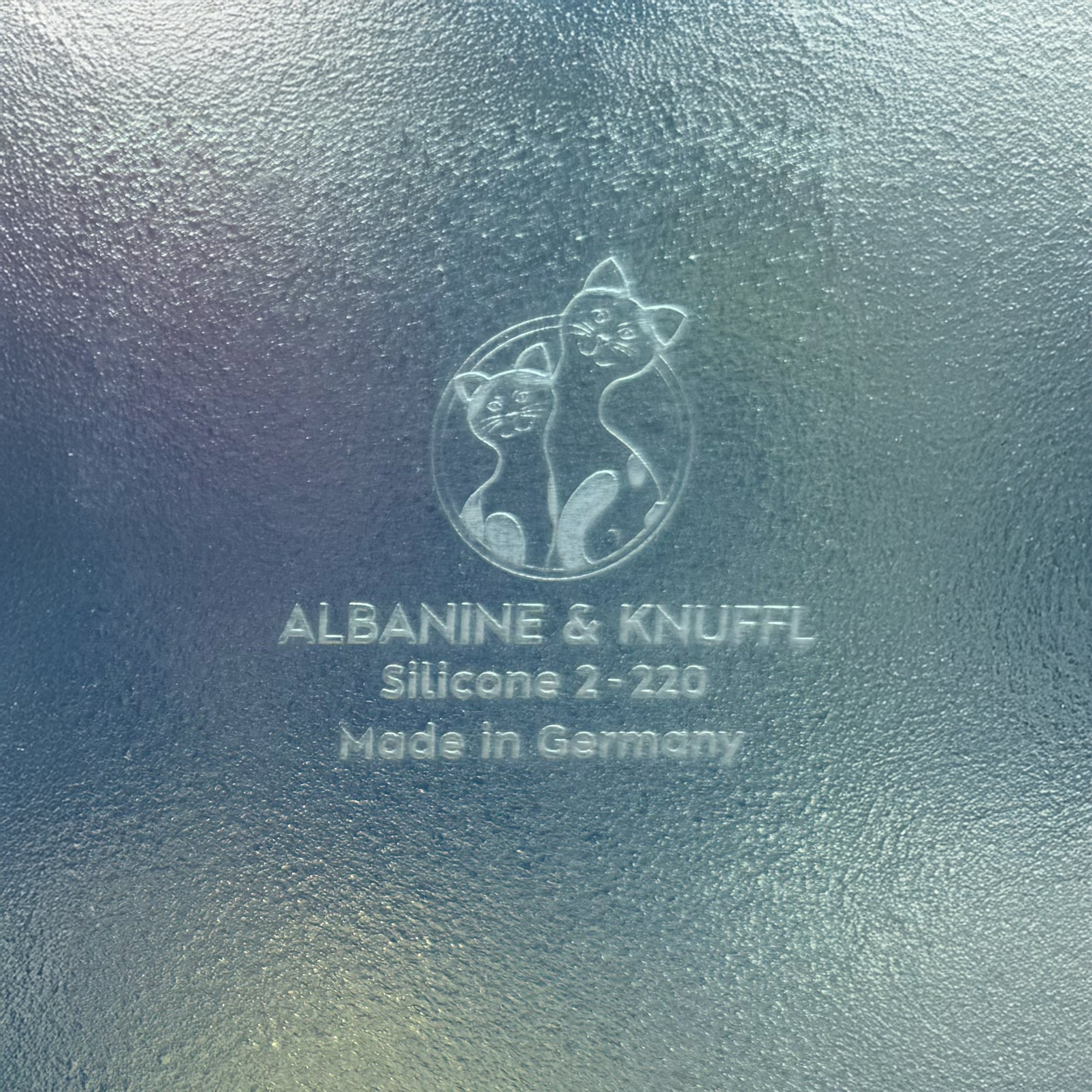 Nahaufnahme Bodenmarke auf Rückseite 8-eckiger farbloser Silikonunterlage für Katzengeschirr, Länge 56 cm und Breite 30,5 cm