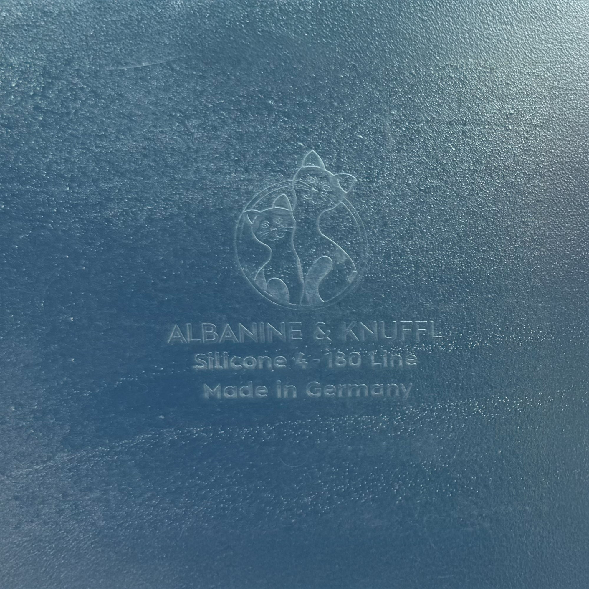 Nahaufnahme Bodenmarke auf Rückseite 8-eckiger farbloser Silikonunterlage für Katzengeschirr, Länge 86,5 cm und Breite 24,5 cm