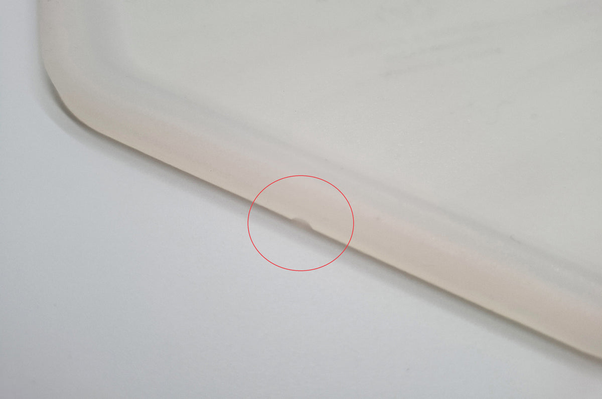 Close-up detail of silicone placemat for cat dinnerware with lower edge damaged by small missing chunk – marked with red circle