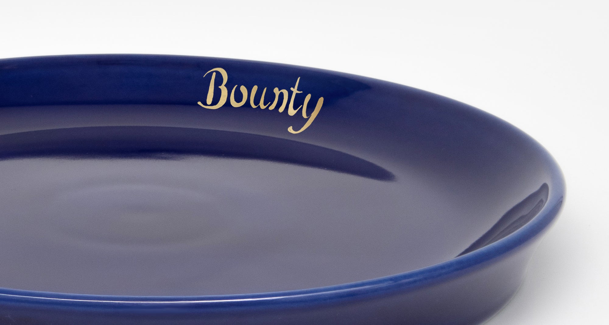 Close-up detail of the inner rim of a dark blue cat plate with personalised gold-coloured inscription
