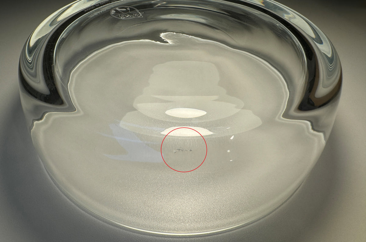 Nahaufnahme Rückseite Trinkschale für Katzen aus Glas mit leichtem Produktionsfehler, gekennzeichnet durch roten Kreis – Ansicht von schräg oben